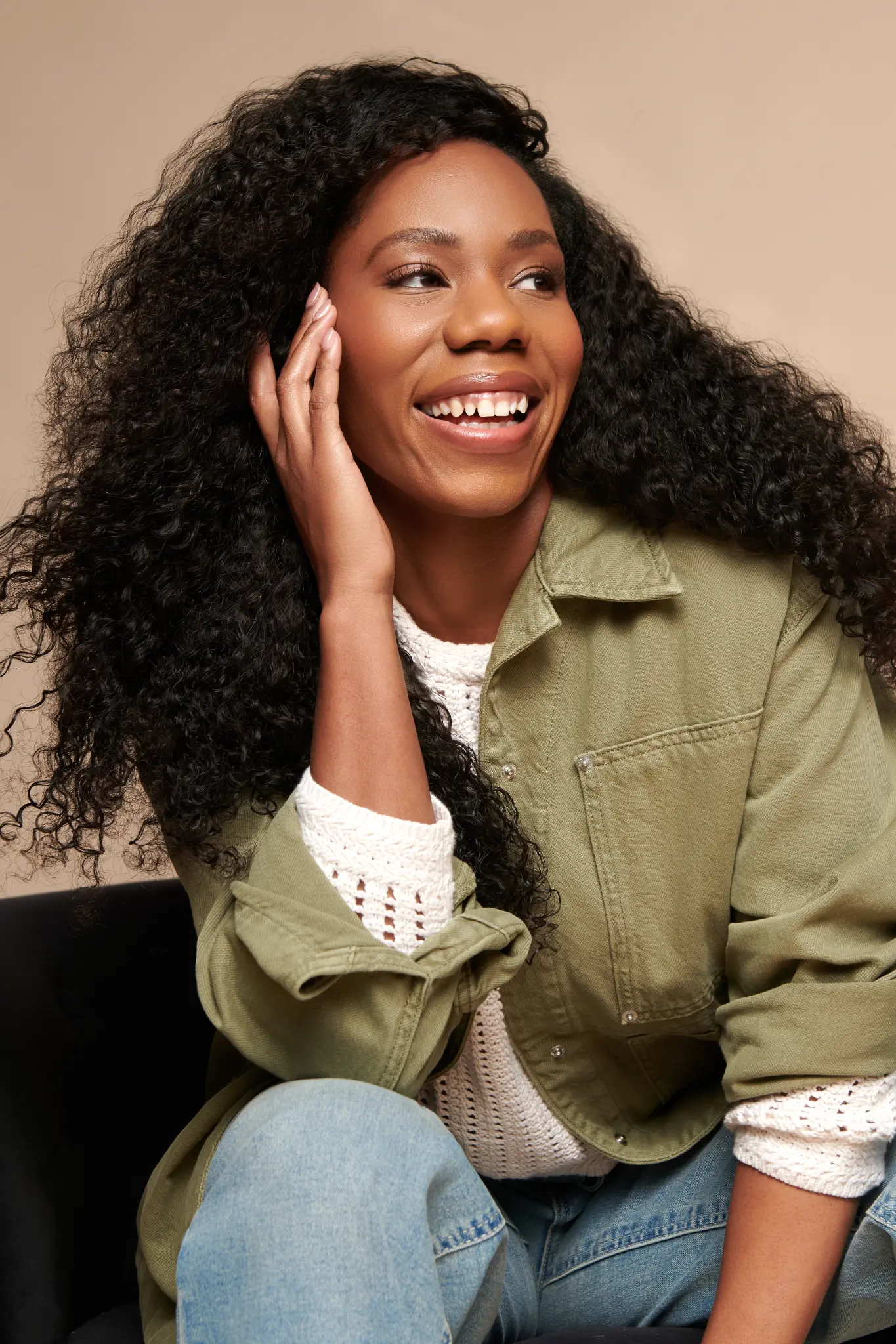 Alesha seated and smiling in a green jacket